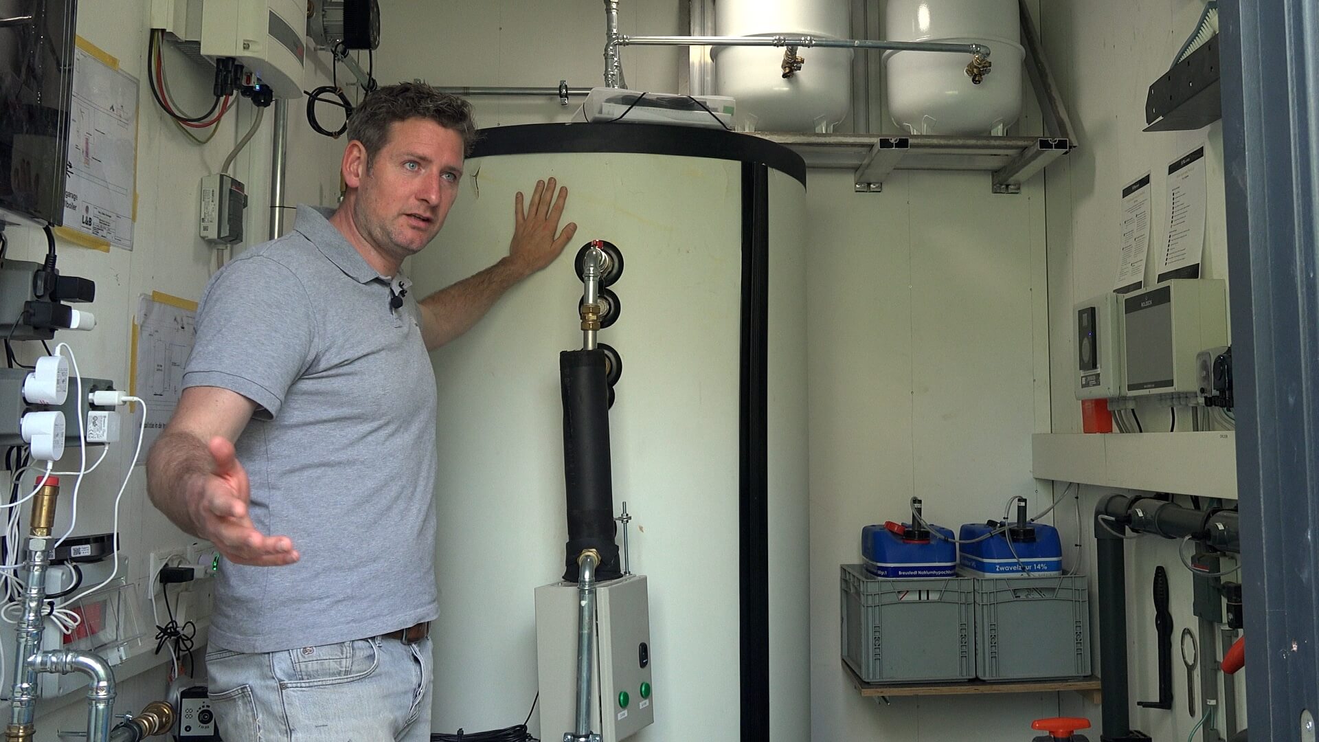Jeroen explaining his setup in the pool's technical room, standing next to a large buffer tank