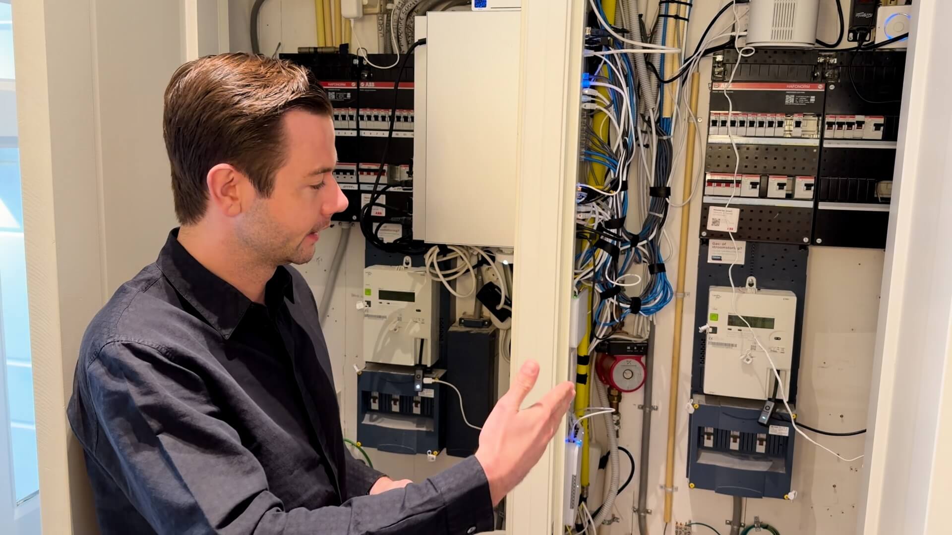 Sam Feldt standing next to an open utility closet showing two smart energy meters