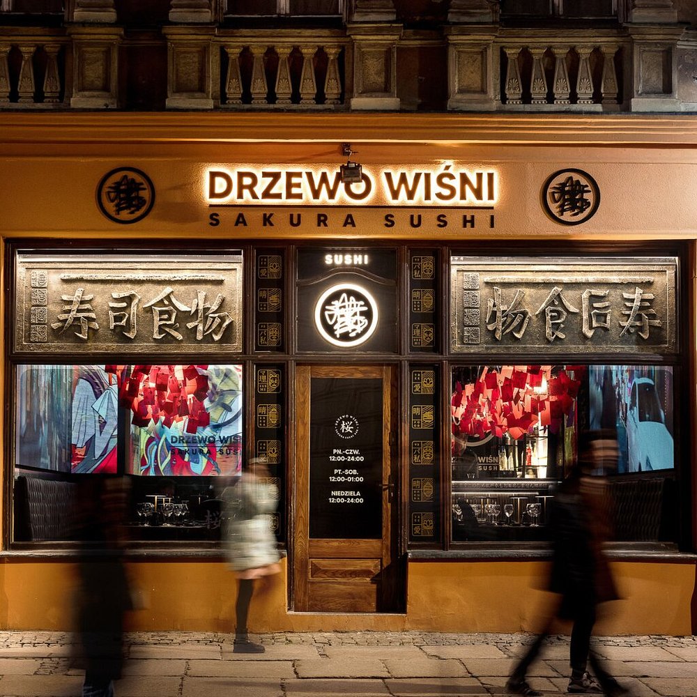 The illuminated facade of Drzewo Wiśni on Poznań’s Old Market Square in the evening