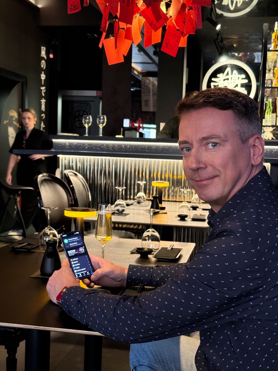 Tomasz Waligóra at a table in Drzewo Wiśni, holding his phone