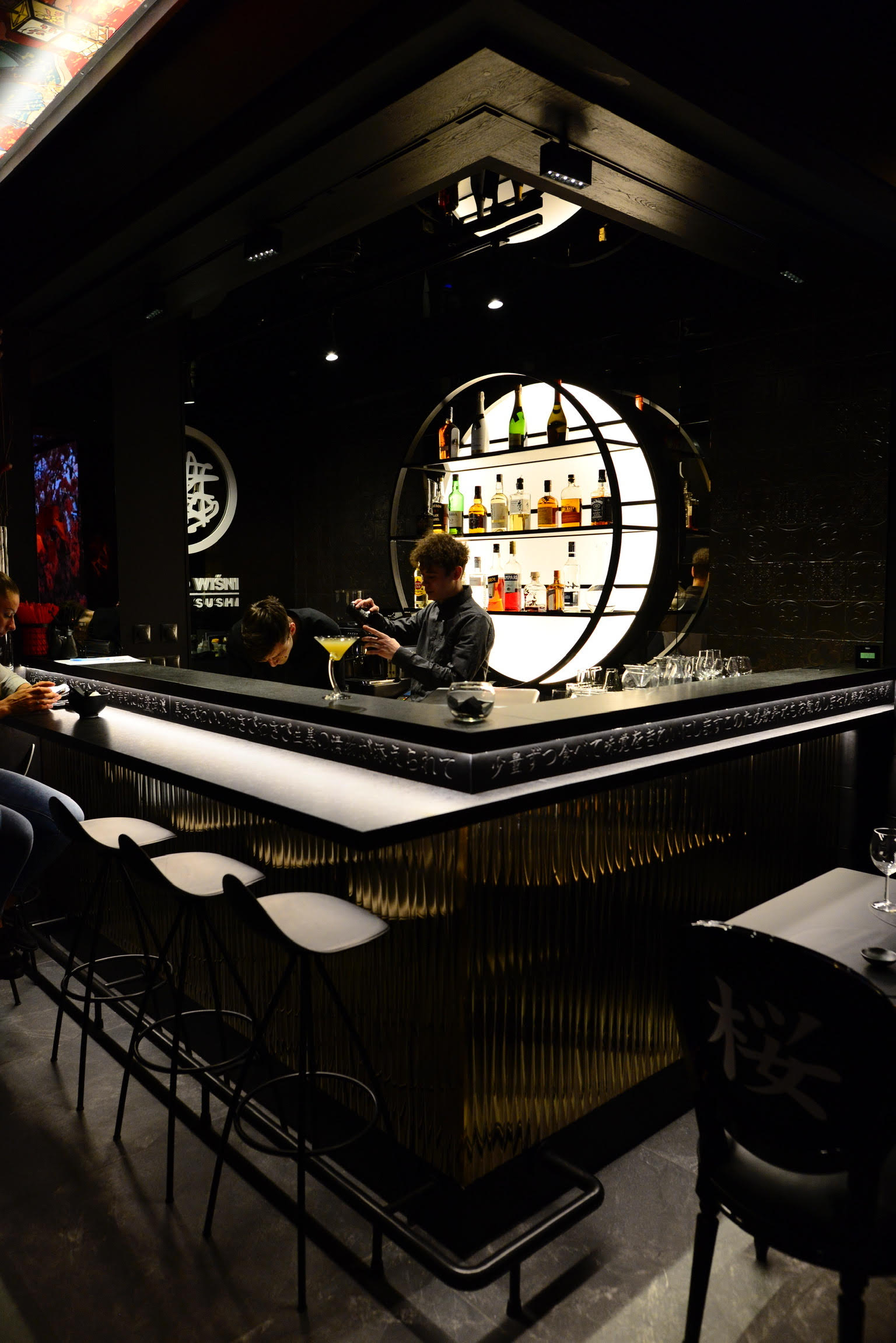 The bar at Drzewo Wiśni, with bottles on backlit circular shelves